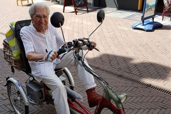 honderdjarige man fietst op van raam easy rider driewieler