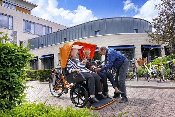 Riksja fiets fotoshoot Van Raam bij zorginstelling instappen