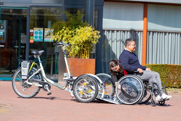Passagier in de eigen rolstoel bij het kantelbare VeloPlus-oprijplateau