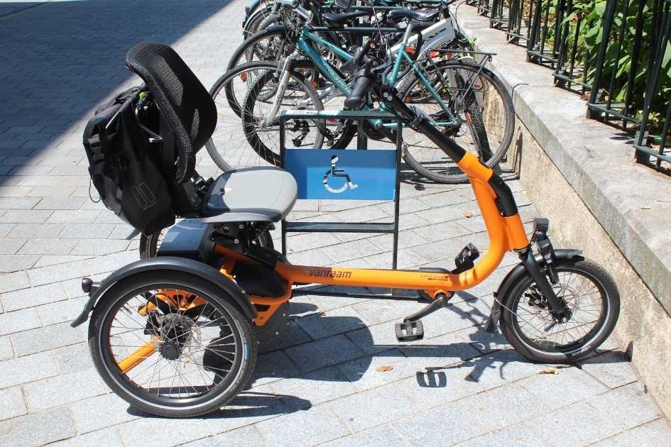 Velo Easy Rider Compact vanRaam orange garé sur une place pour PMR Velo Easy Rider Compact vanRaam orange garé sur une place pour PMR